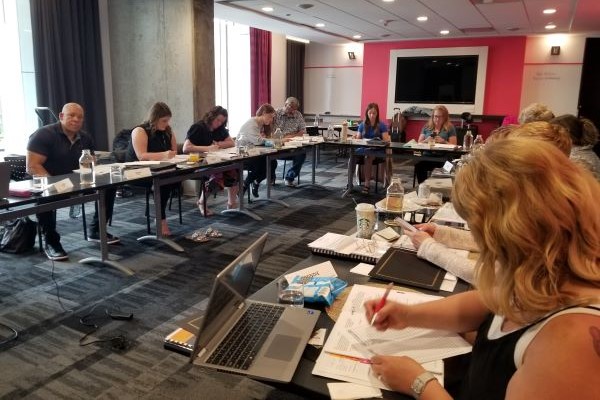 A dozen individuals working at a U-shaped conference table.
