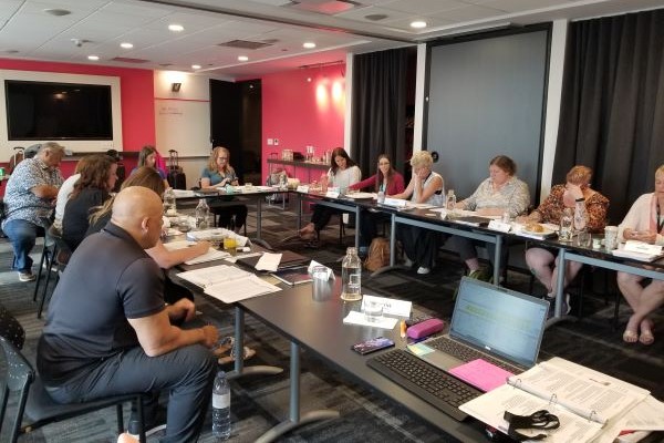 A dozen individuals working at a U-shaped conference table.