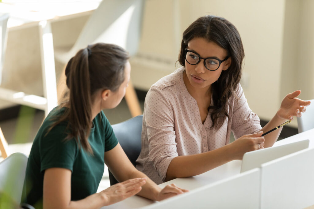 Serious Young African American Businesswoman Talking With Female Leader In