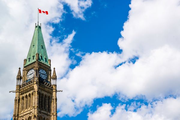 Photograph of the Peace Tower at the Parliament Buildings of Canada, with a blue sky and puffy white clouds in the background.
