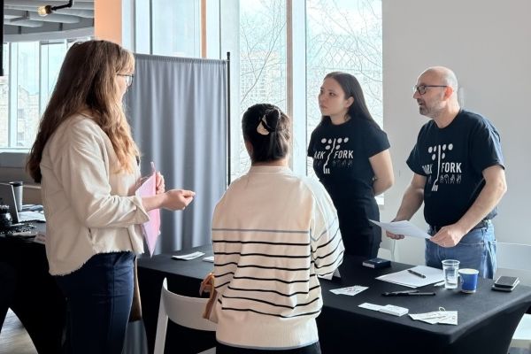 Two job seekers speak to two employers at a job fair.