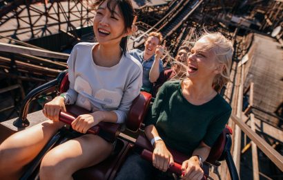 Two women in a roller coaster going up the ride with excitement on their face.