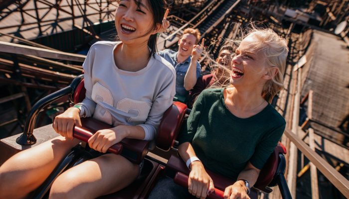 Two women in a roller coaster going up the ride with excitement on their face.