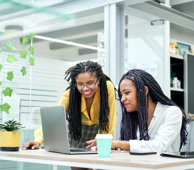 Two women of colour looking at a computer screen in interest in an office.