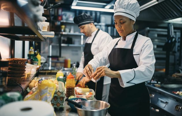 African American Professional Cook Cracking An Egg While Preparing Meal