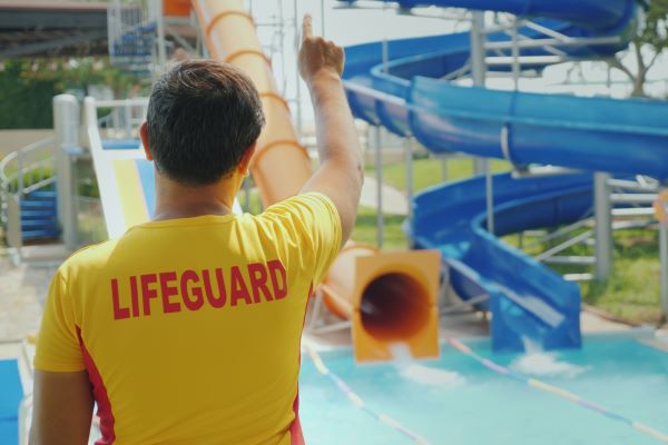 Male lifeguard of a waterpark with his back turned to the camera.