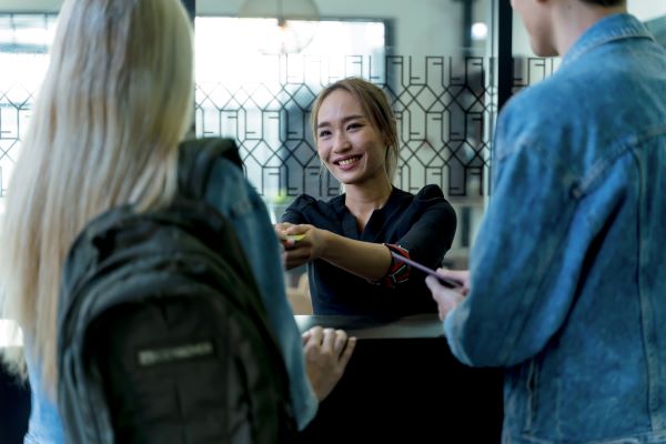 A front desk agent hands a room key to two hotel guests.